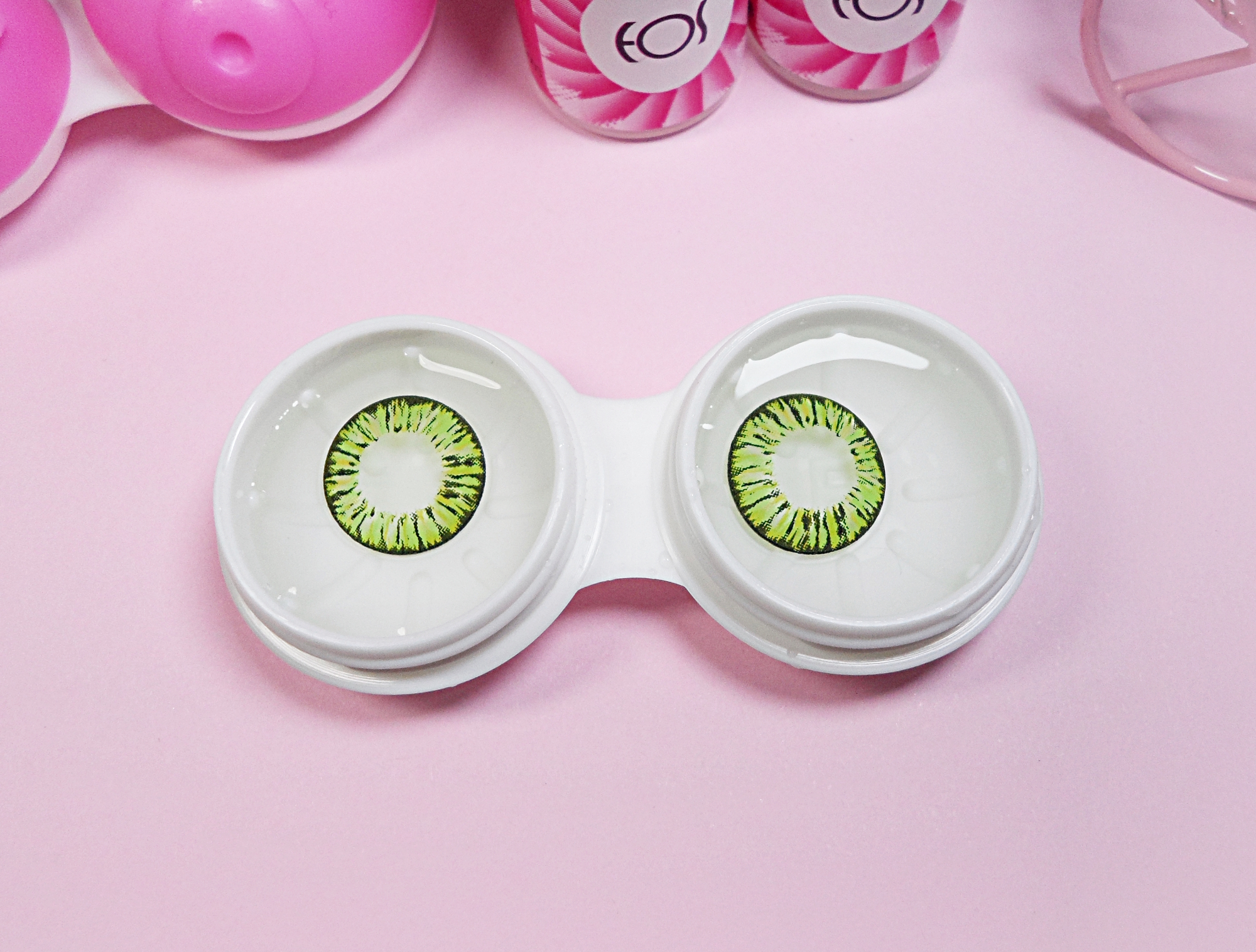 close-up of a green circle lenses in solution on a rosy studio's background