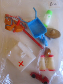 Bag, priced at $2, with six vintage dolls' house toys inside including a hobby horse, a pair of binoculars, a toy car and a first aid bag.