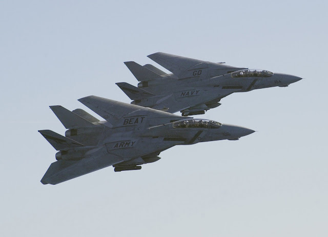 A pair of F-14D Tomcats flyby with the text "Go Navy" "Beat Army" on top of  the wings.