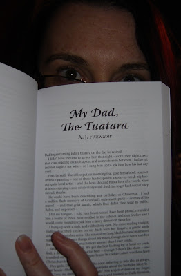 The author peeks over the top of a book, open to the first page of her story