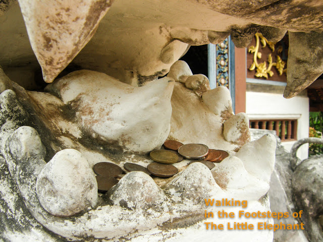 Coins in the mouths of a dragon at Wat Nong Bua in Nan, North Thailand