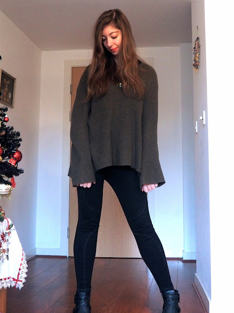 Oversized - outfit of large, loose green jumper, black t-shirt, black seam detailed leggings, and black heeled ankle boots