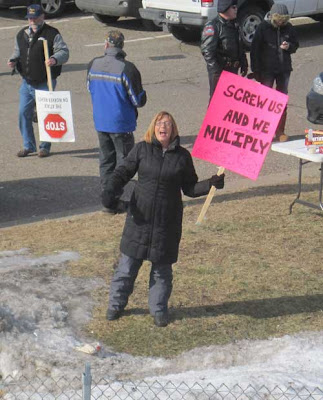 Woman with a hot pink sign reading Screw Us and We Multiply