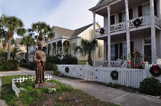 Geisha wood carving of a geisha girl in front of Victorian houses