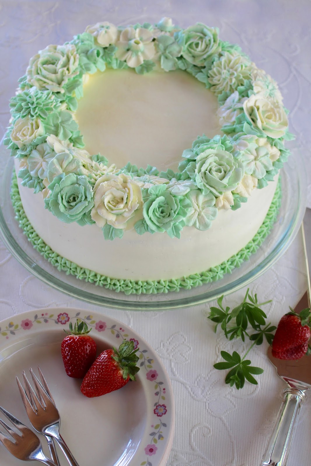 Erdbeer-Waldmeister-Torte mit einem Kranz aus Buttercreme-Blüten Erdbeer-Waldmeister-Torte mit einem Kranz aus Buttercreme-Blüten