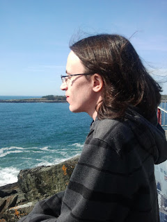 Photo of a young man with long hair looking over the water