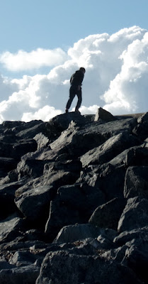 boy climbs pile of rocks with cloudy background pile of granite rocks by pyramids centre