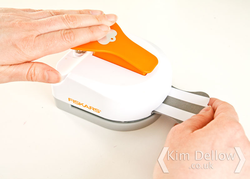 Place the tag in the hole punch slot of the Fiskars 3 in 1 Tag maker