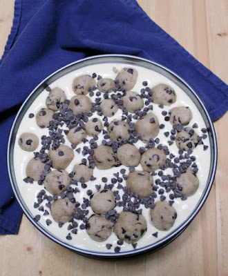 springform pan filled with cheesecake batter, mini chocolate chips and balls of chocolate chip cookie dough