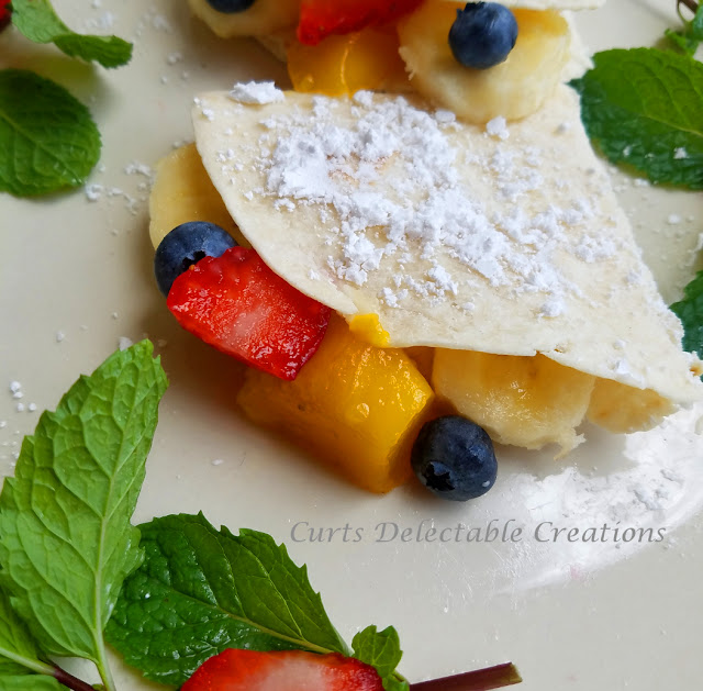 This is a picture of a freshly cooked and plated crepe filled with fruit. 