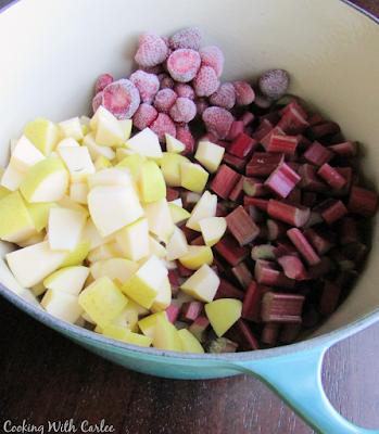 This delicious sauce is so simple to make and so delicious! Strawberry, rhubarb and apples get sweetened with just a touch of honey for a great snack. It is perfect eaten alone or a fun dip for your animal crackers! pot full of chopped apples and rhubarb and frozen strawberries