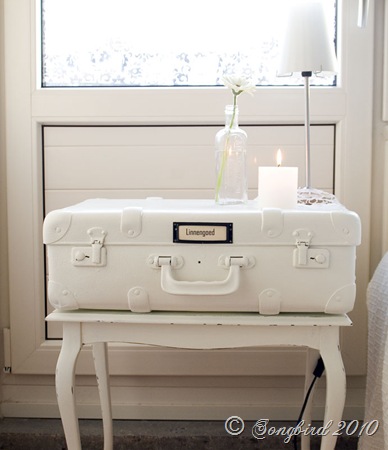 This white vintage suitcase paired with a simple candle and flower vase is calming and serene. 