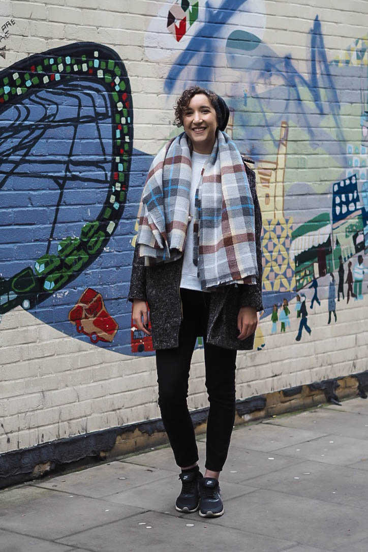 Fashion blogger wearing blanket scarf, black skinny jeans and Nike trainers