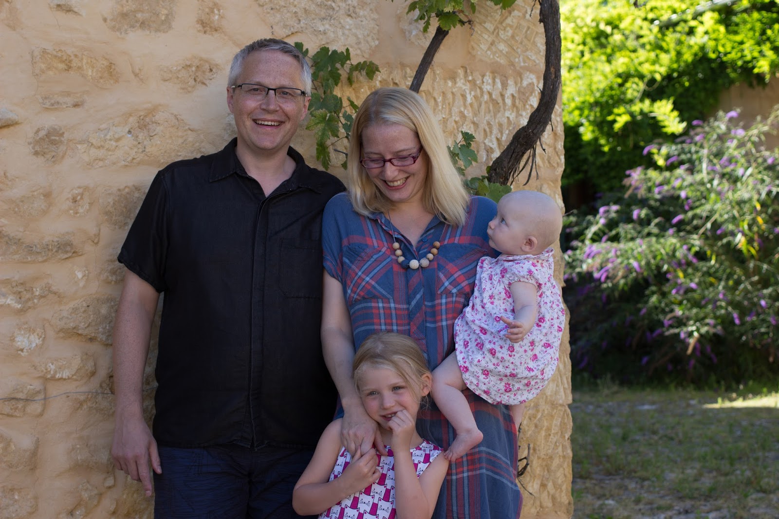 A family of four next to a brick wall with a vine in France