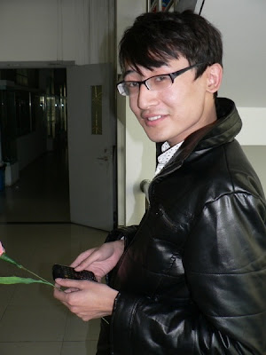 male student in black jacket holding mobile phone