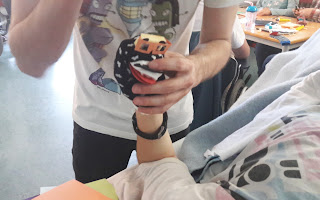 Atividade do Museu da Marioneta O Pedro ajuda um aluno na cama a construir a sua marioneta