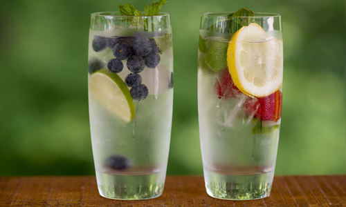 Two glasses of enhanced water with berries and herbs for flavor and color.