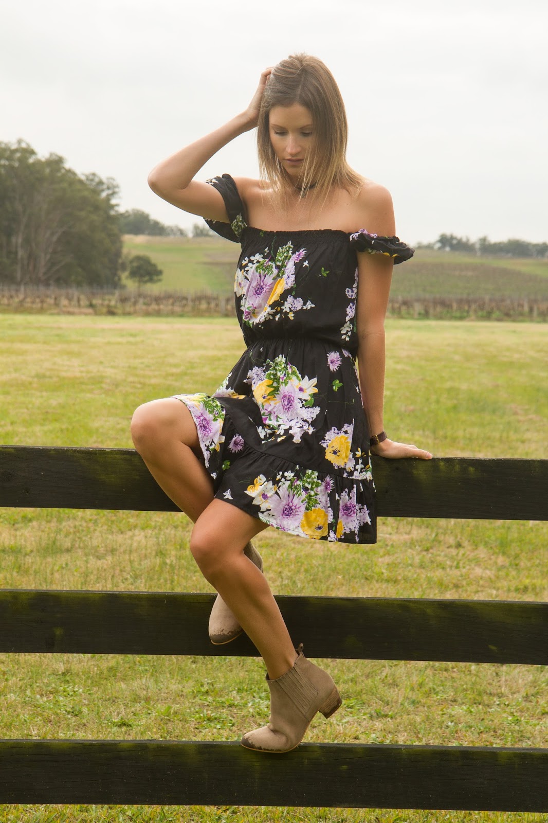 Fashion and travel blogger, Alison Hutchinson, is wearing a KAYVALYA off the shoulder dress in black floral print in Hunter Valley, Australia