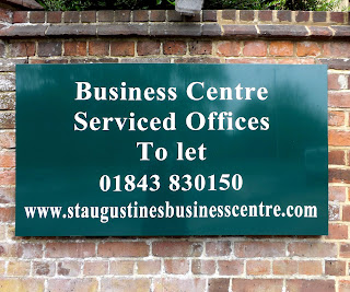 Green metal sign, with white text with business centre written on it.