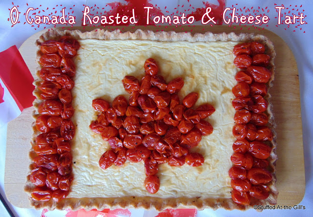 Roasted Tomato & Cheese Tart sitting on a cutting board. Roasted grape tomatoes are laid on top of the rectangular tart in the shape of the Canadian Flag.