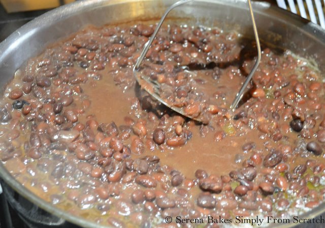 Cooked Black Beans being fried in a frying pan and mashed.