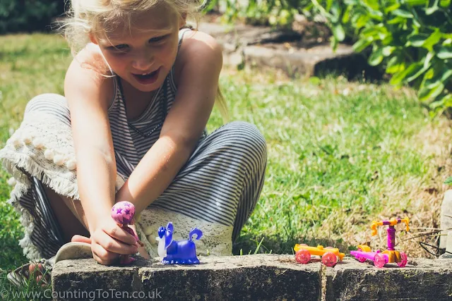 A young girl playing with little Vampirina figures in a garden