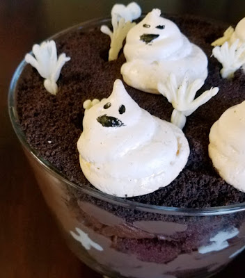 So sweet and so spooooooky! This trifle is full of chocolate goodness with sweet meringue ghosts and white chocolate bones. It's a great Halloween treat! layers of chocolate in glass trifle bowl with white chocolate hands and meringue ghosts on top