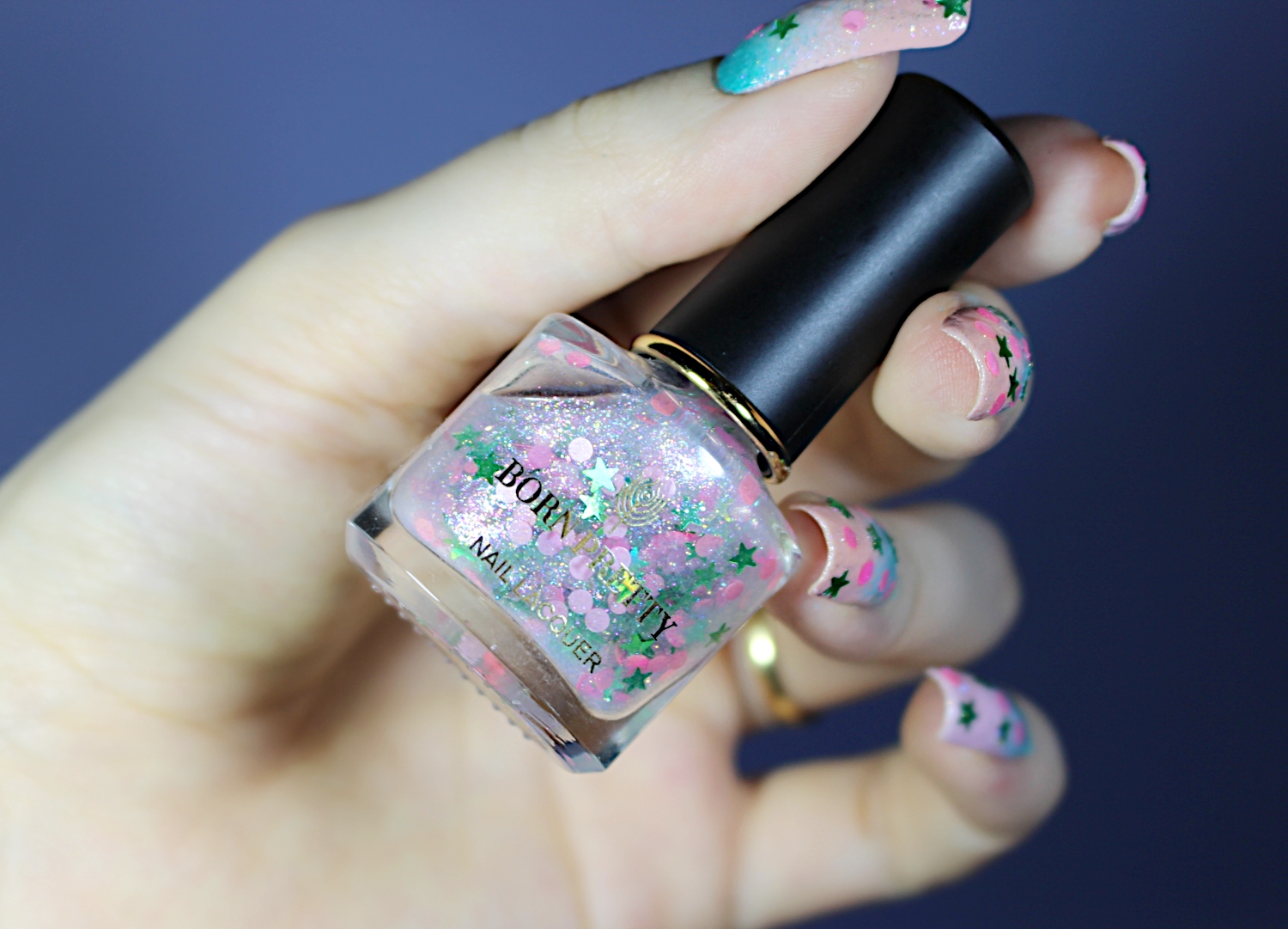 close-up of female hand with a glitter and sequin nail look in soft baby pink colors