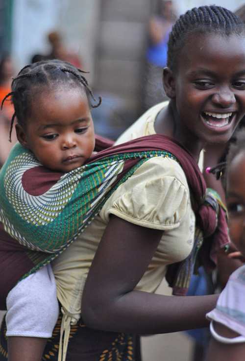 Mãe carrega bebé nas costas com uma capulana Mãe carrega bebé nas costas com uma capulana