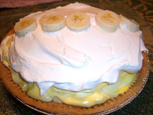 old fashioned homemade banana cream pie in a pie plate with whipped cream on top homemade banana pudding, bananas on top and whipped cream