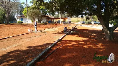 Acertando a terra para a execução da rua com o calçamento com pedras tipo de piso com pedrisco compactado com as guias de pedra, com pedra folheta, em rua da entrada da sede da fazenda em Atibaia-SP e a execução do paisagismo.