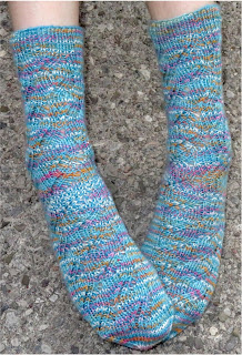 Someone wearing a pair of ribbed lace socks.  The socks are blue with flecks of white, pink, and yellow. 