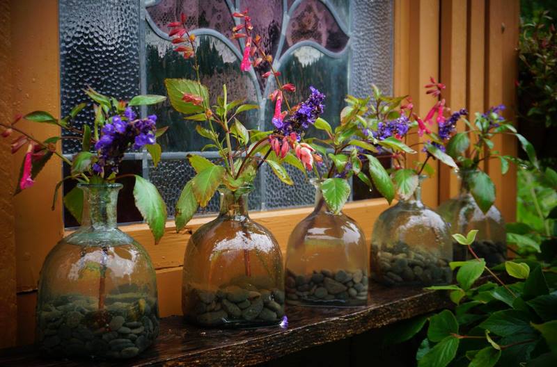 botellas de cristal con piedras dentro y una rama de salvia