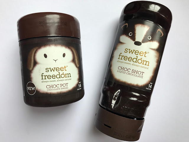 2 brown plastic containers: a small tub with a rabbit on saying sweet freedom choc pot chocolate spread and a tube with a badger on saying sweet freedom choc shot liquid chocolate