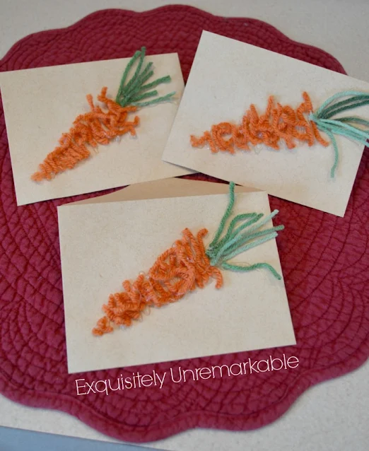Three brown envelopes with yarn carrots glued to the top