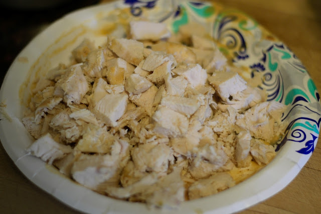 The fully cooked chicken, diced, on a paper plate.  