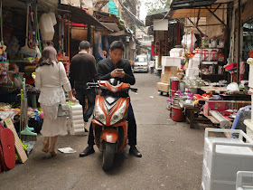 man using his mobile phone while sitting on motor scooter at Yanjiatang Lane (晏家塘巷) in Changsha