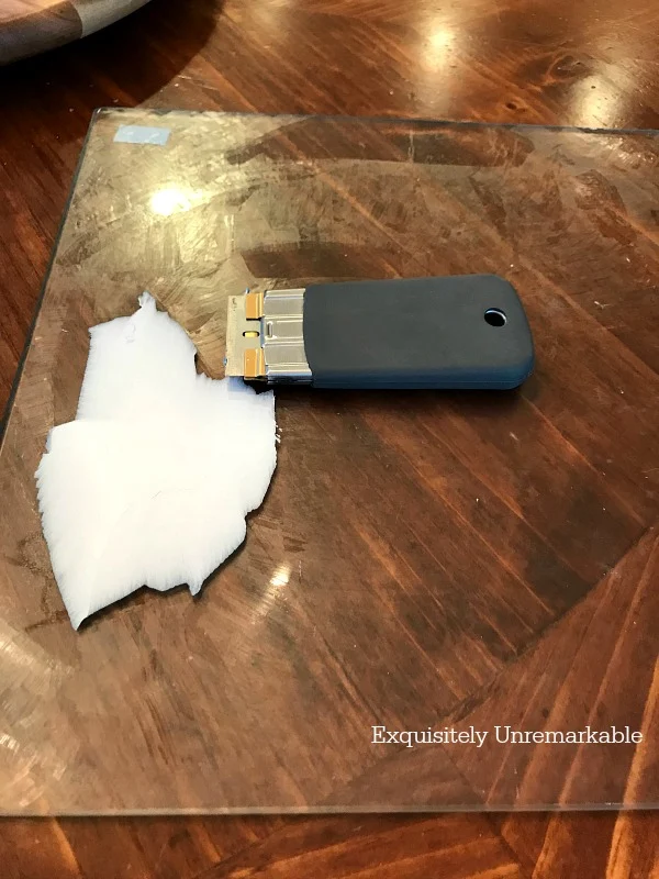 Using A Razor To Scrape Glass Cutting Board Sticker