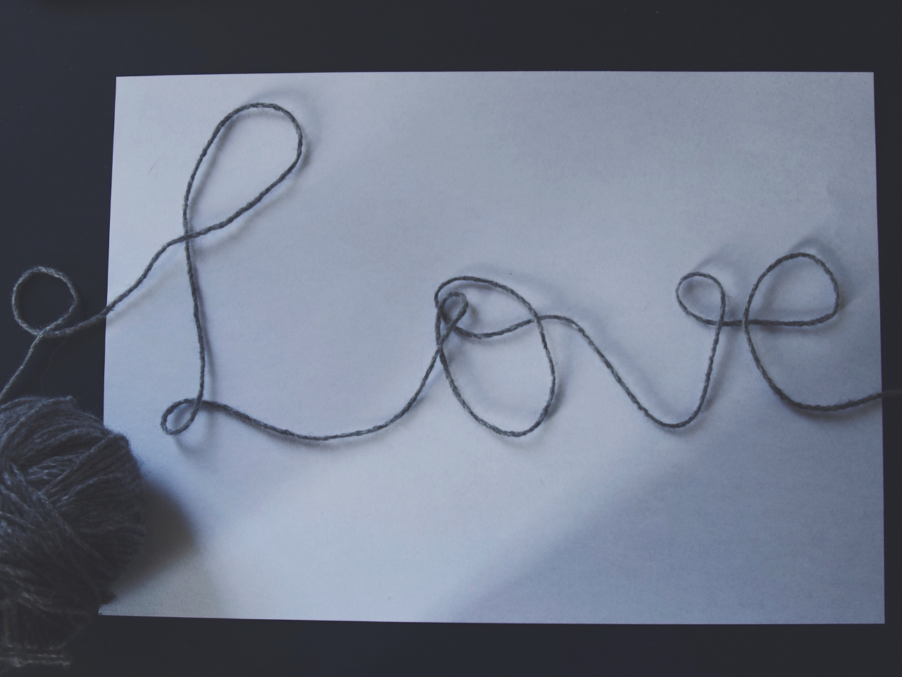 Love is made out to be such a complicated thing – when really it isn't. On a white sheet of paper the word »Love« laid out of grey wool