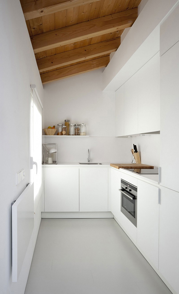 Small white kitchen with wooden ceiling beams. Villa Piedad by Marta Badiola. Photo by Francisco Berreteaga
