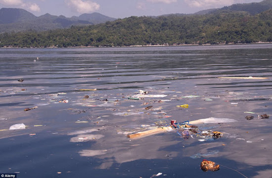 surfista de indonesia deslizándose en ola llena de basura