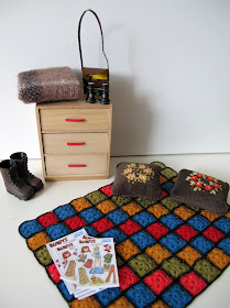 One-twelfth scale miniature 1940s chest of drawers, afghan rug, embroidered cushions, tramping boots, blanket and binoculars.