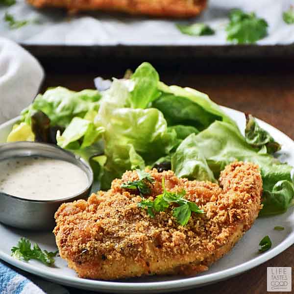 Crispy Air Fried Chicken Breasts on a plate with salad and a dish of dressing for a delicious low carb keto dinner
