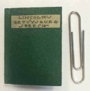 The cover for a miniature edition of the Gettysburg Addressed, positioned next to a paperclip for scale.