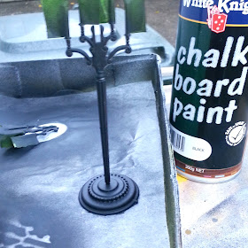 One-twelfth scale plastic candelabra pieces painted black,on a background of baking paper, with a can of chalkboard paint next to them.