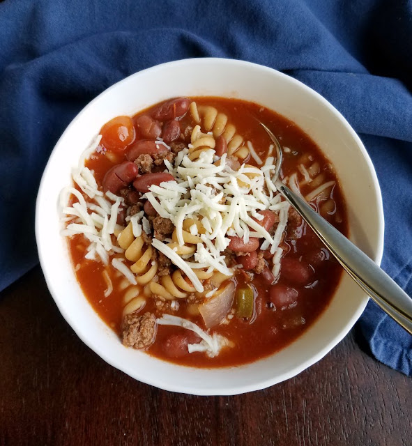 This is the chili soup we grew up with. It has beef and beans and plenty of macaroni noodles too! bowl of chili with pasta in it and cheese on top