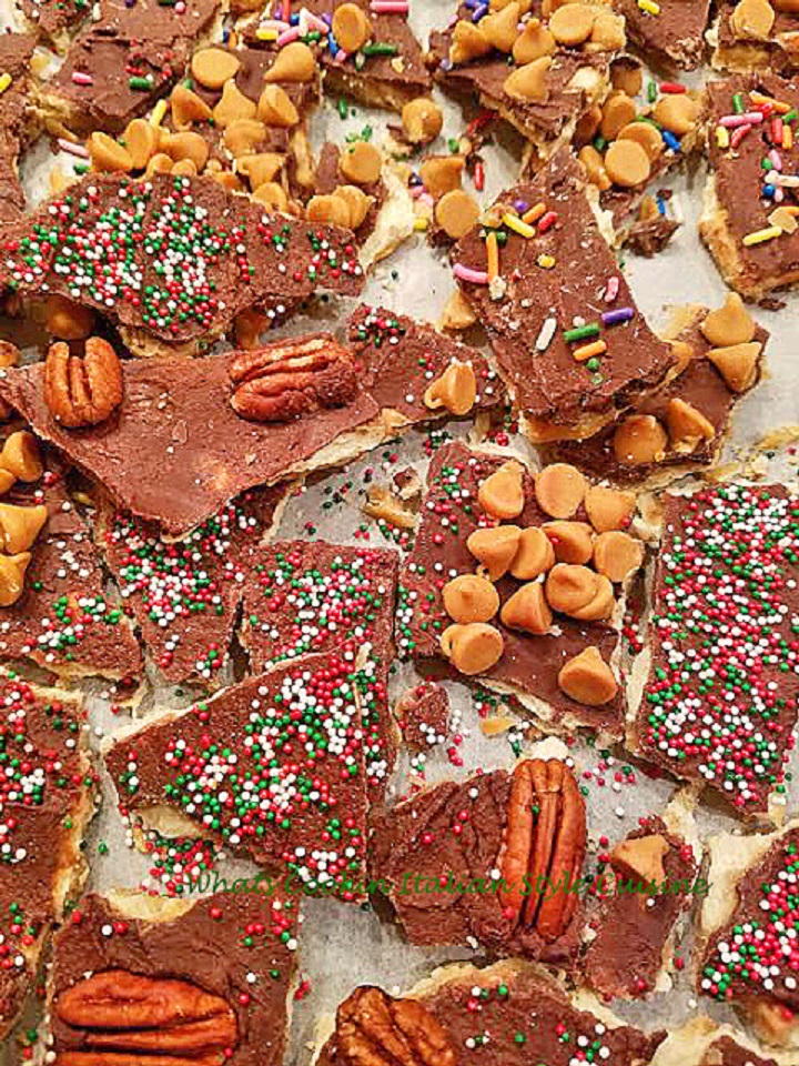 this is a homemade salted caramel toffee bite candy made with a cracker crust into toffee bites. It has caramel on top along with colored sprinkles, chocolate melted and pecans. It also has peanut butter and caramel chips and some white chocolate chips.