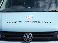 Printed small ball of daisy flowers in the centre of eggshell van bonnet, with black vinyl lettering showing the website address 'www.flowersbysp.co.uk'.