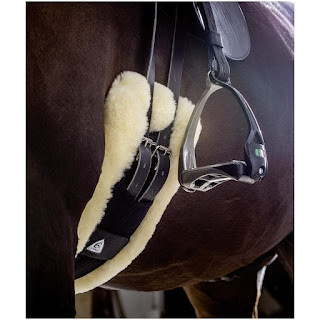 A low shot of a horse's tummy wearing a sheepskin girth and straight facing stirrups
