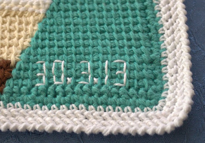 Close-up of the bottom right corner of a placemat where the date (30 March 2013) is embroidered in white cotton on the green fabric.